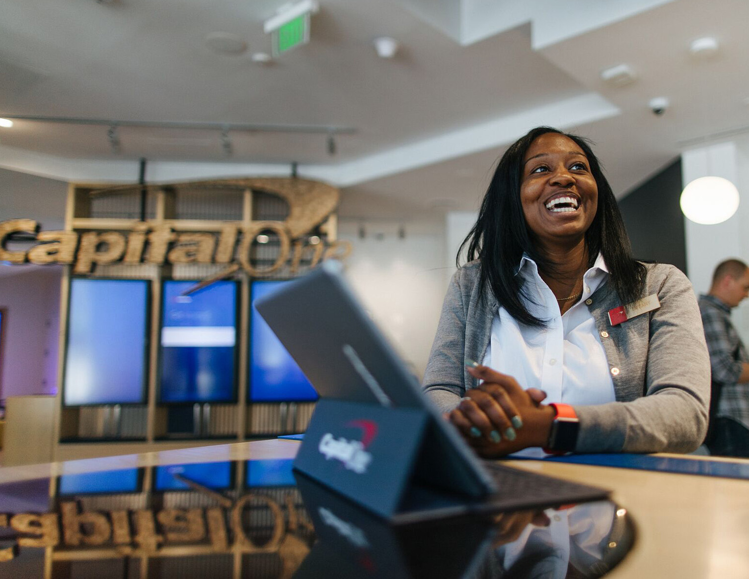 Capital One Cafe Ambassador stands at a cafe table and smiles